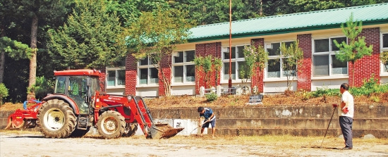 귀촌인 백씨가 캠핑시설로 운영하던 원주시 S면 폐고 운동장에서 지난 20일 마을 주민들이 포크레인 등으로 정리작업을 하고 있다. 마을개발이원회는 백씨가 떠난 뒤 6개월가량 방치됐던 폐교를 최근 주민교육센터로 바꾸는 공사를 하고 있다. 원주=김태호 기자